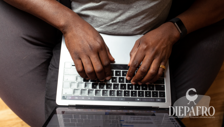 Fotografia tirada por cima de um homem negro digitando em um notebook